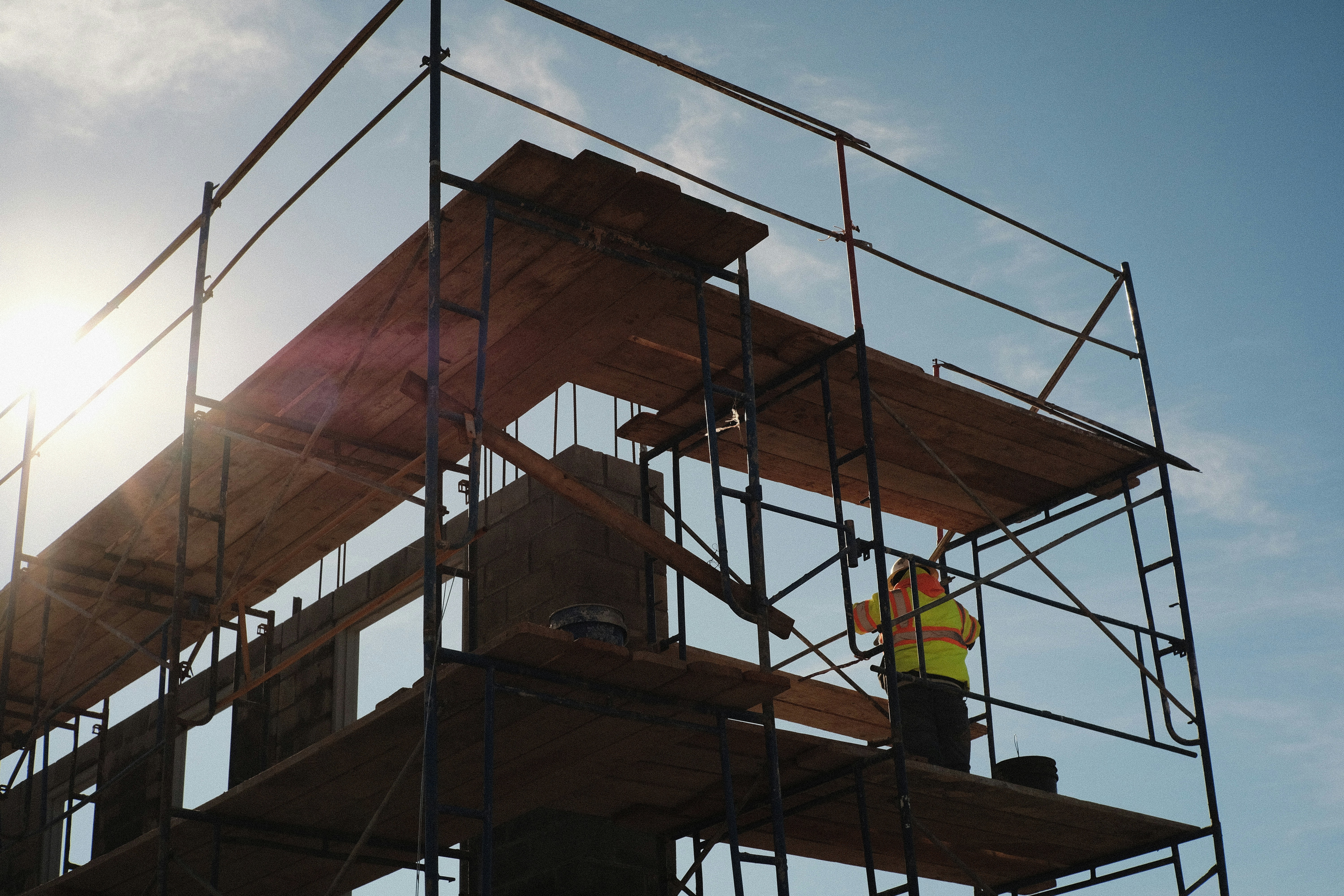 Workers on scaffolding construction site at sunset